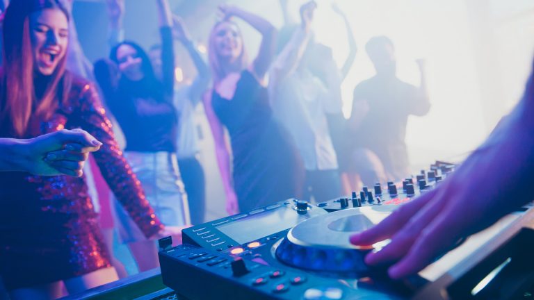 Dj playing stereo loud sound rhythm set for attractive stylish cheerful positive, people crowd hang out enjoying evening having fun time festive concert at fashionable modern nightclub